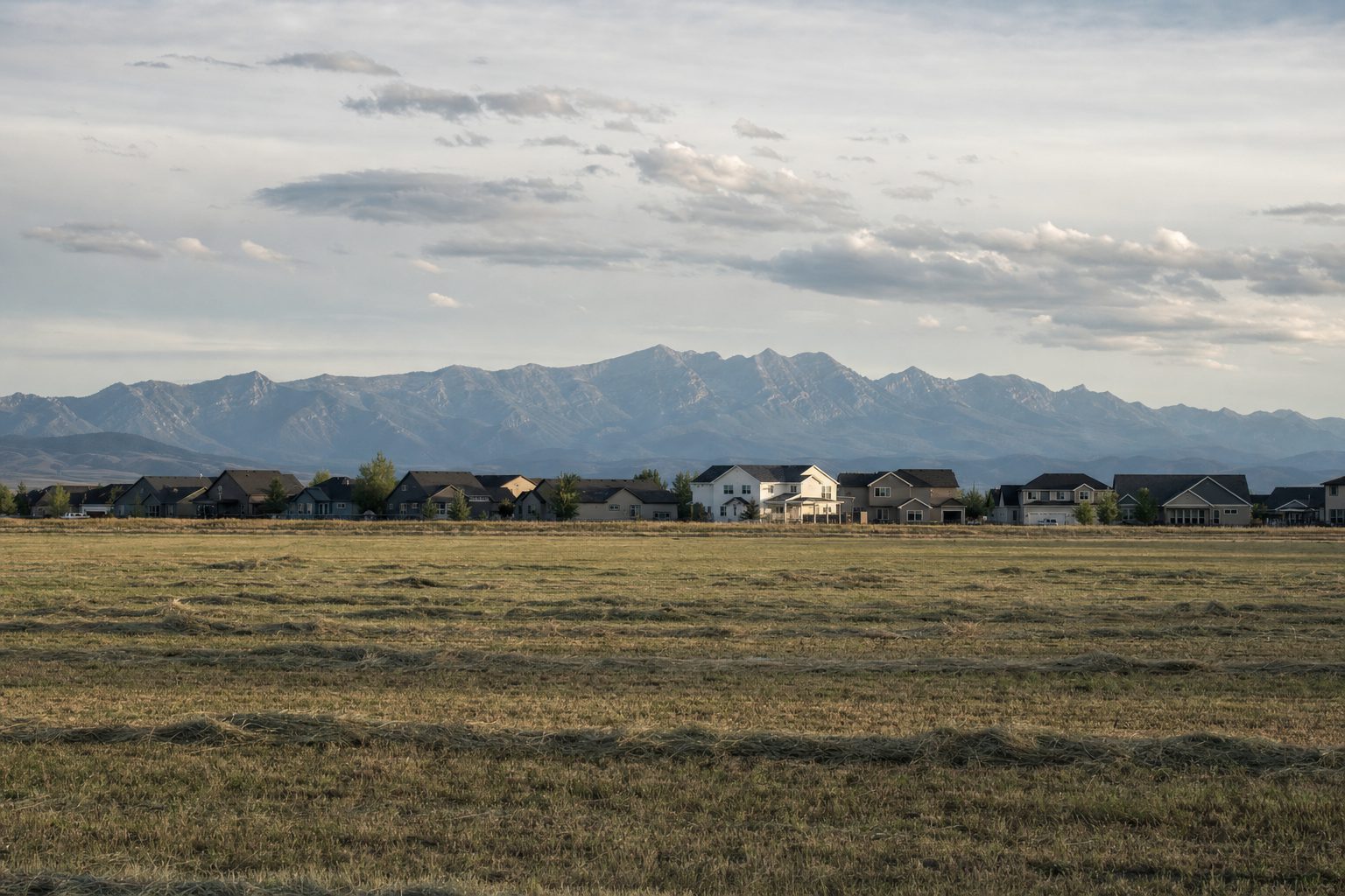 Homes at the edge of a hayfield near Belgrade with the Bridger Range behind